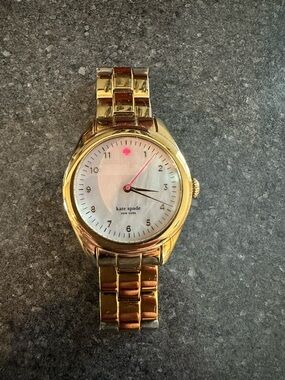 Kate Spade gold watch with white dial and pink accent